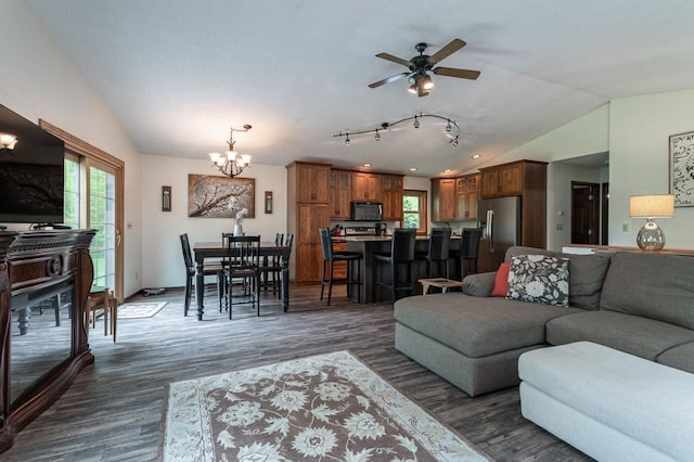 living room featuring ceiling fan with notable chandelier, a healthy amount of sunlight, dark hardwood / wood-style flooring, and vaulted ceiling