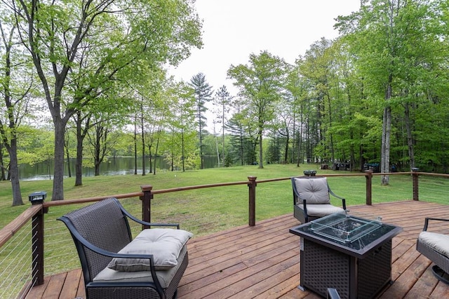 deck featuring a water view, an outdoor fire pit, and a lawn