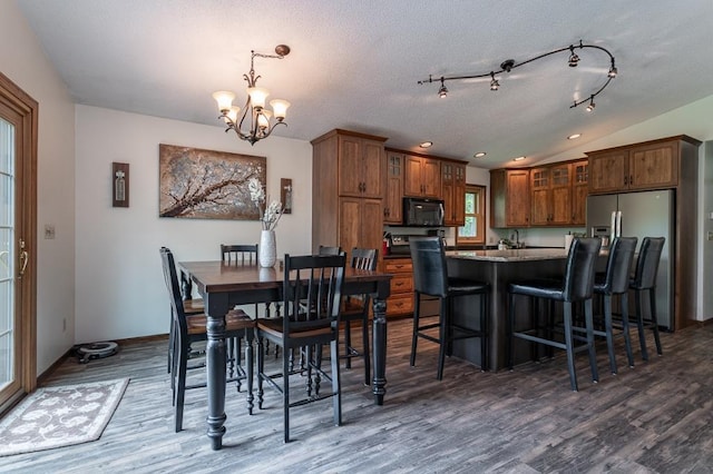 dining area featuring dark hardwood / wood-style flooring, lofted ceiling, a textured ceiling, and an inviting chandelier