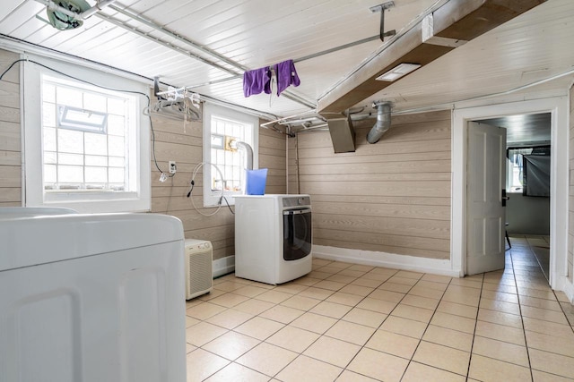 clothes washing area featuring wooden walls, washer / dryer, and light tile floors