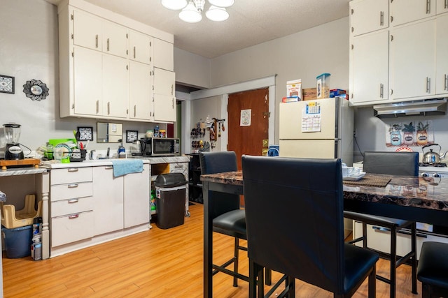 kitchen featuring white cabinetry, light wood-type flooring, and white refrigerator