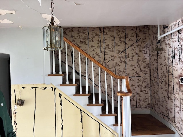 stairs with a notable chandelier