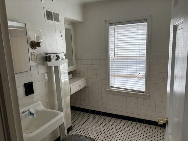 bathroom with tile patterned floors, a healthy amount of sunlight, sink, and tile walls