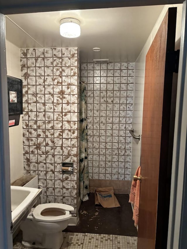 bathroom with tile patterned flooring, a shower with shower curtain, toilet, and tile walls