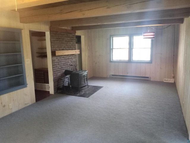 unfurnished living room featuring a baseboard heating unit, brick wall, beam ceiling, a wood stove, and dark carpet