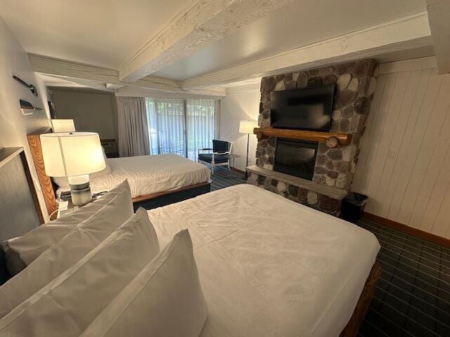 bedroom featuring beamed ceiling and a fireplace