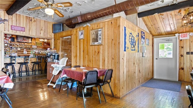 14549 Plummer Rd, Weyerhaeuser, WI 54895 - dining space featuring ceiling fan, wood-type flooring, lofted ceiling with beams, bar, and wood walls