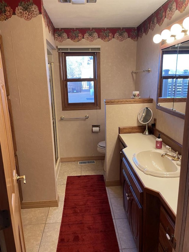 bathroom featuring tile patterned flooring, vanity, toilet, and a shower with shower door