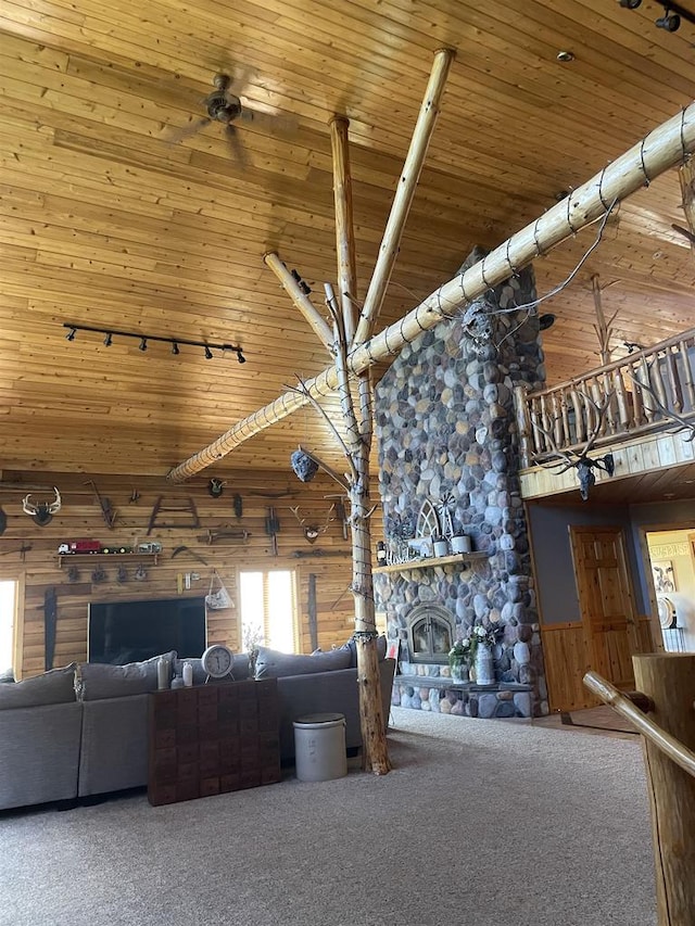 unfurnished living room with wooden ceiling, a high ceiling, carpet floors, wooden walls, and a fireplace