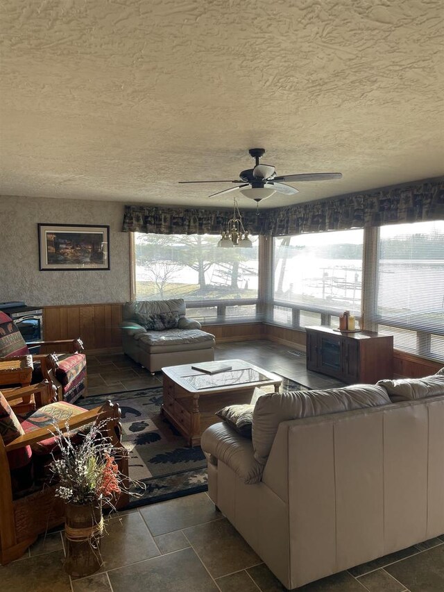 living room featuring ceiling fan, a textured ceiling, and a wealth of natural light