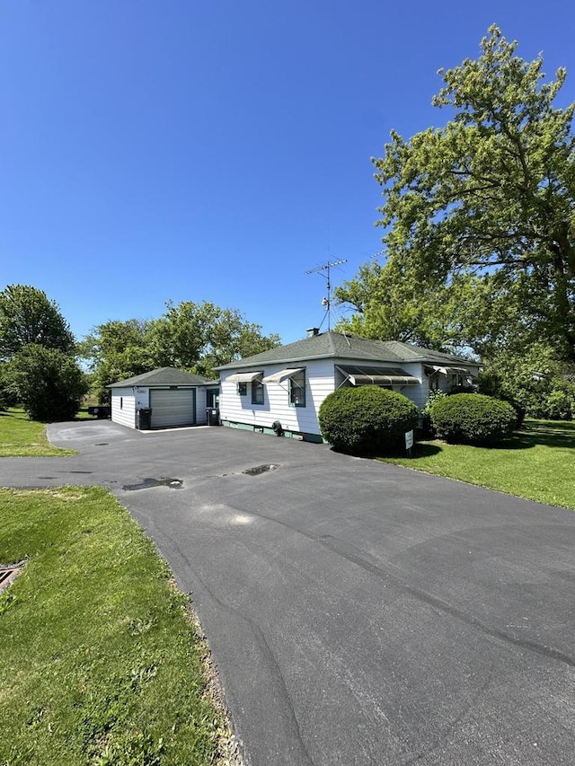 view of front facade featuring a front yard, an outdoor structure, and a garage