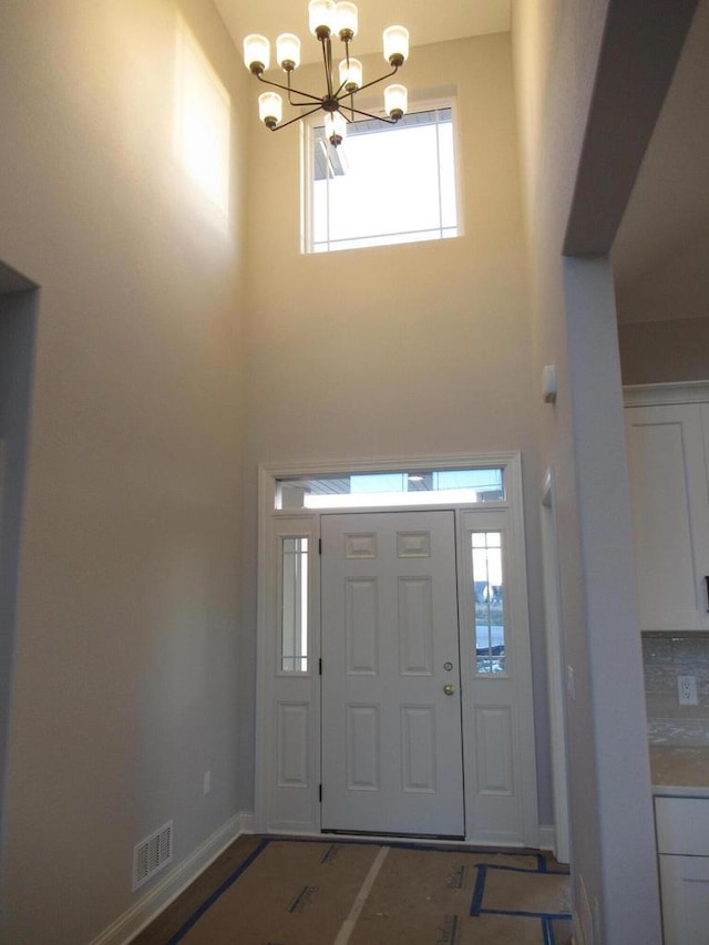 foyer featuring a towering ceiling and a notable chandelier