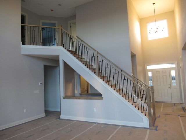 entryway featuring a high ceiling, hardwood / wood-style flooring, a wealth of natural light, and a notable chandelier