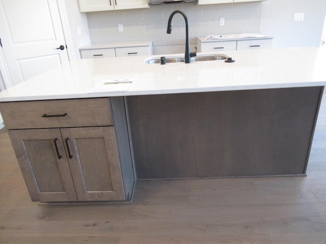 kitchen featuring tasteful backsplash, white cabinetry, sink, and light hardwood / wood-style flooring