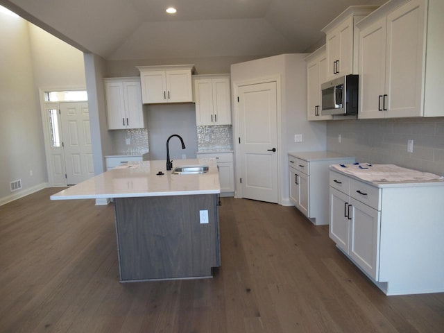 kitchen featuring dark hardwood / wood-style flooring, sink, an island with sink, and white cabinets