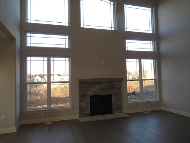 unfurnished living room with a high ceiling, dark hardwood / wood-style floors, and a fireplace