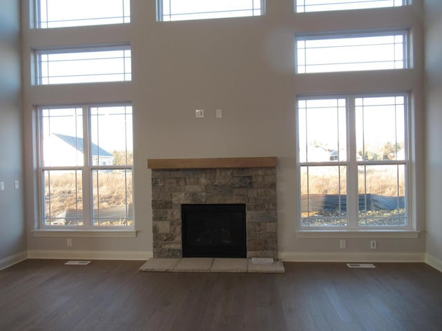 unfurnished living room with a high ceiling, dark hardwood / wood-style floors, and a fireplace