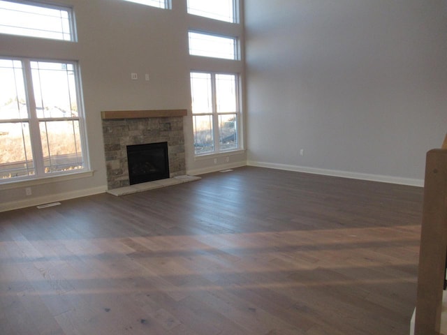 unfurnished living room featuring a fireplace, dark hardwood / wood-style flooring, and a high ceiling