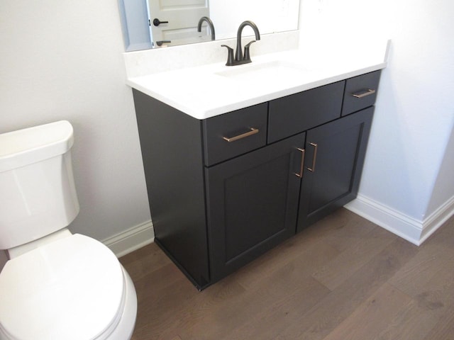 bathroom with vanity, toilet, and hardwood / wood-style floors