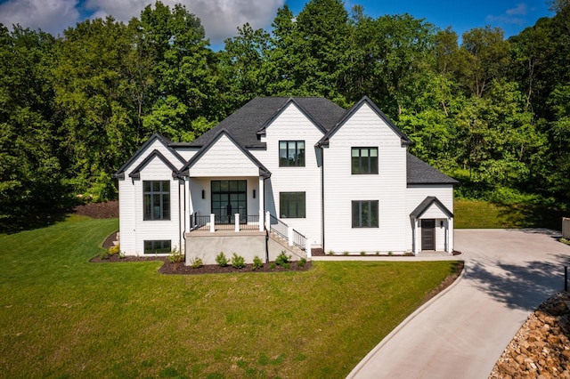 modern farmhouse style home with covered porch, a front yard, and a garage