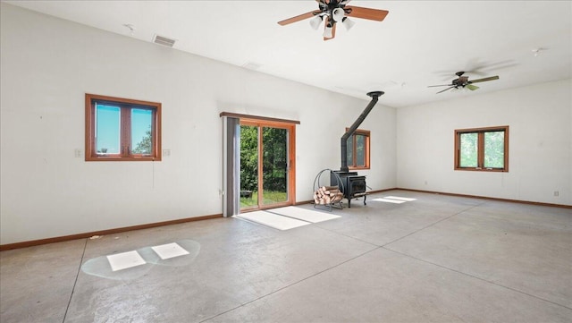 unfurnished living room with ceiling fan and a wood stove