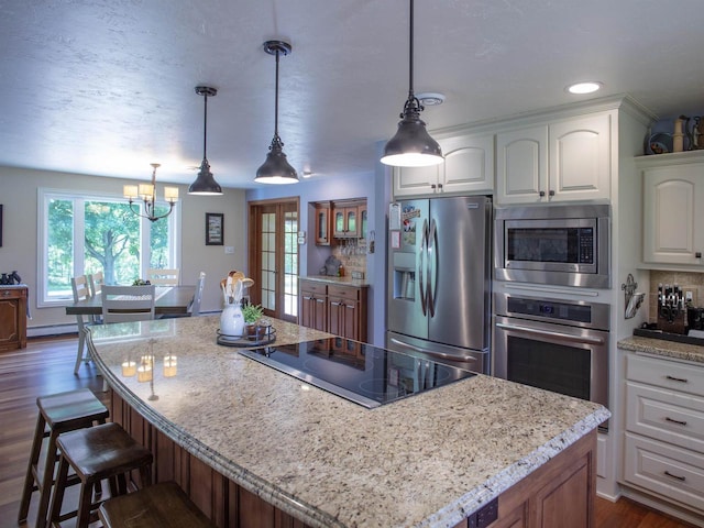 kitchen featuring white cabinets, stainless steel appliances, decorative light fixtures, and a kitchen island