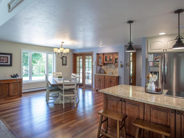 kitchen featuring stainless steel fridge, baseboard heating, tasteful backsplash, decorative light fixtures, and dark hardwood / wood-style flooring