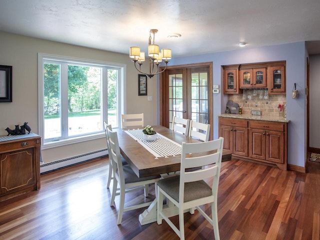 dining area featuring french doors, a baseboard radiator, an inviting chandelier, and dark wood-type flooring