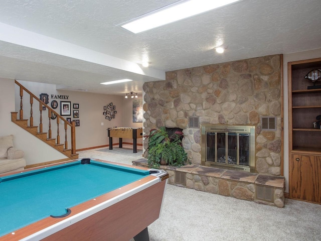 game room with carpet, a stone fireplace, a textured ceiling, and pool table