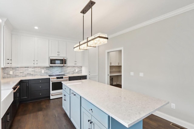 kitchen with white microwave, white cabinetry, tasteful backsplash, gas range, and crown molding