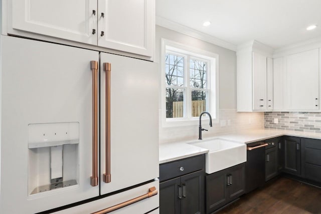 kitchen featuring high end white fridge, decorative backsplash, a sink, and white cabinets