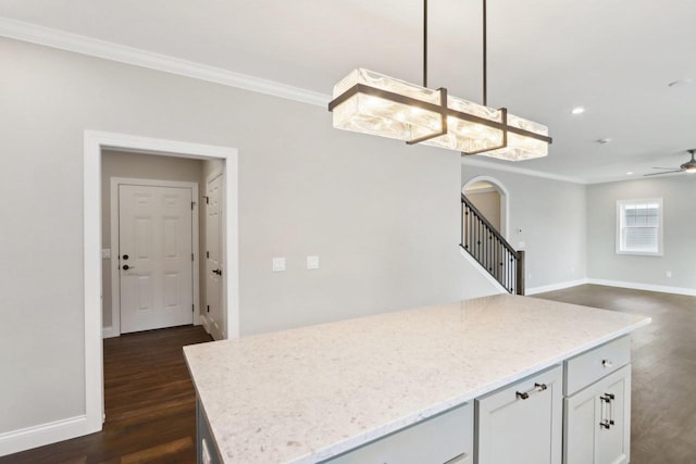 kitchen with arched walkways, dark wood-style flooring, baseboards, and crown molding