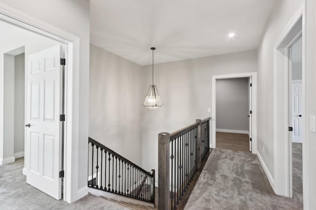 corridor with baseboards, carpet flooring, and an upstairs landing