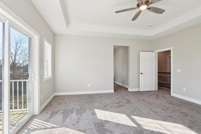 unfurnished bedroom featuring baseboards, a tray ceiling, and carpet flooring