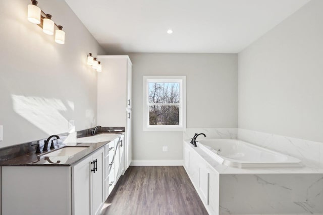 bathroom featuring double vanity, a garden tub, a sink, and wood finished floors