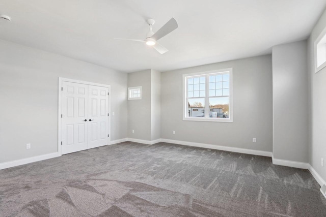 spare room featuring ceiling fan, dark carpet, and baseboards