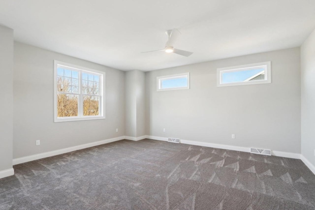 carpeted spare room with baseboards, visible vents, and ceiling fan