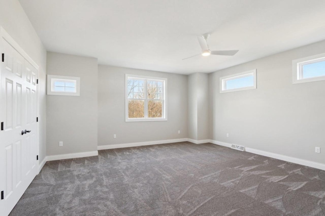 carpeted empty room featuring baseboards, visible vents, and a ceiling fan