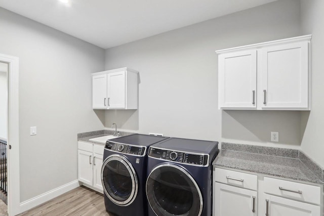 laundry room with washer and dryer, cabinet space, a sink, light wood-type flooring, and baseboards