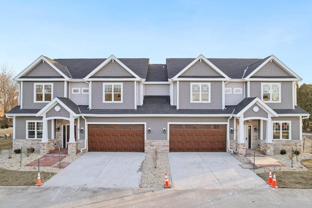 view of front of house featuring driveway, stone siding, and an attached garage