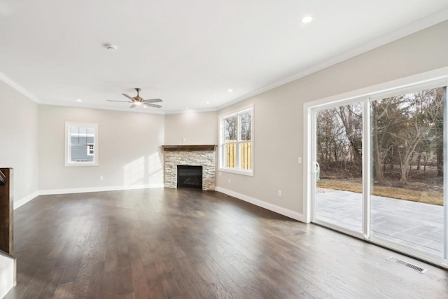 unfurnished living room with a healthy amount of sunlight, visible vents, ornamental molding, and a stone fireplace