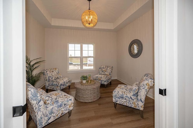 sitting room with hardwood / wood-style flooring, a notable chandelier, and a tray ceiling