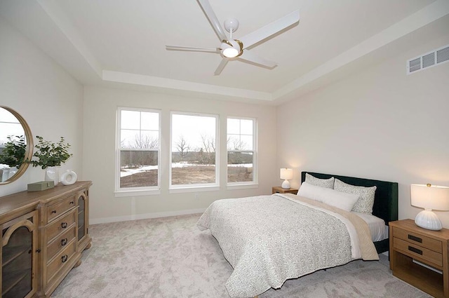 bedroom with light colored carpet, a raised ceiling, and ceiling fan