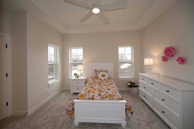 bedroom featuring a raised ceiling, ceiling fan, and light colored carpet