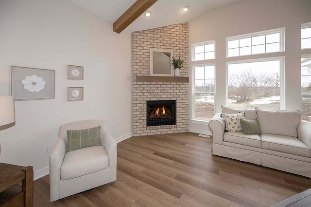 living room featuring a fireplace, beam ceiling, hardwood / wood-style flooring, and high vaulted ceiling