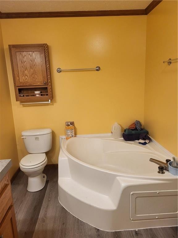 bathroom with ornamental molding, a washtub, vanity, wood-type flooring, and toilet