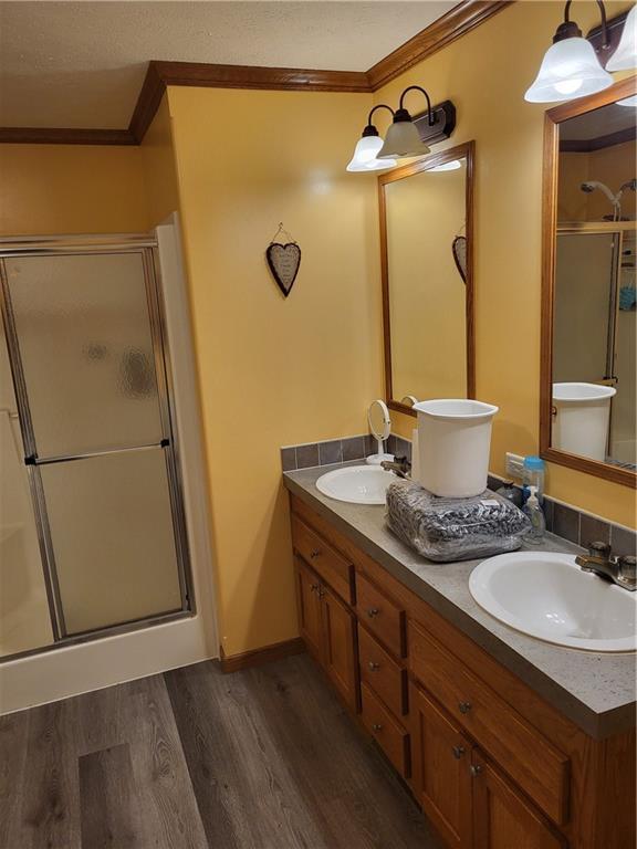 bathroom with vanity, hardwood / wood-style flooring, a shower with shower door, and ornamental molding