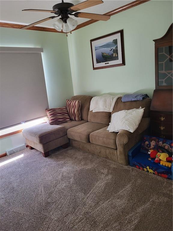 carpeted living room featuring ceiling fan and crown molding