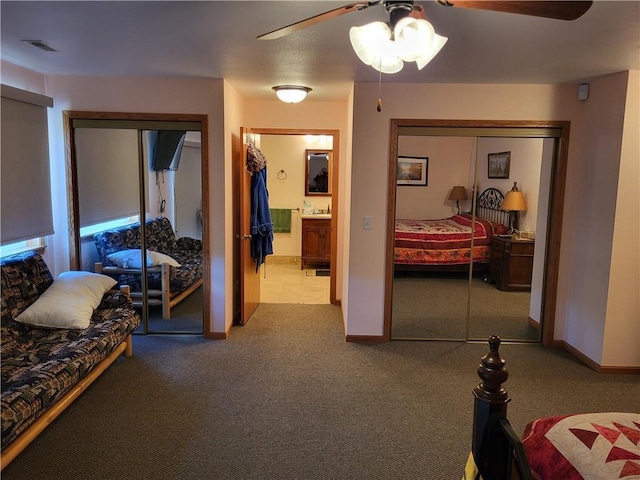 carpeted bedroom featuring ceiling fan and two closets