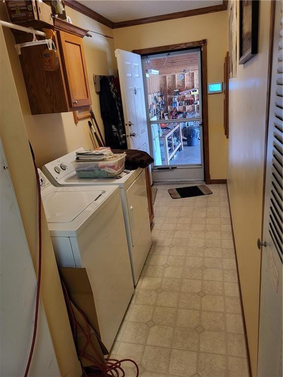 clothes washing area featuring washer and dryer, crown molding, and cabinets